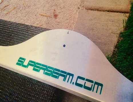 A white surfboard with the word " superteam. Com ".