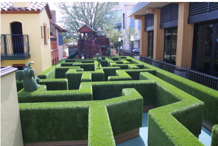 A large maze of grass is in the middle of an alley.