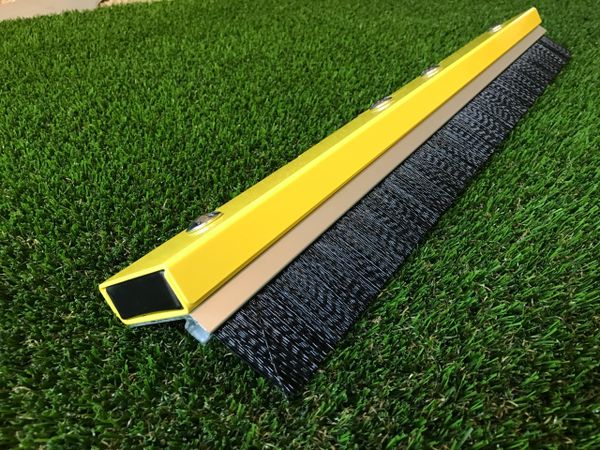 A yellow plastic rail with black rubber tracks on the grass.