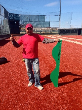 A man holding up a green sign on the red ground.