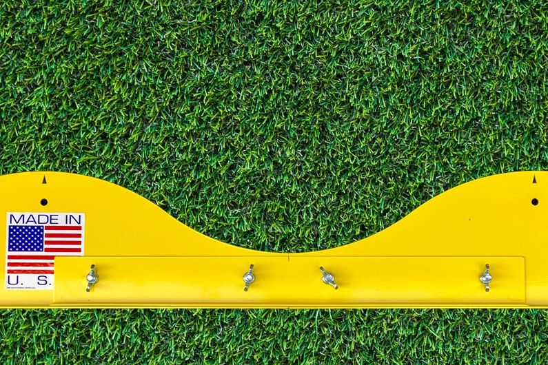 A yellow wall mounted coat rack on the grass.